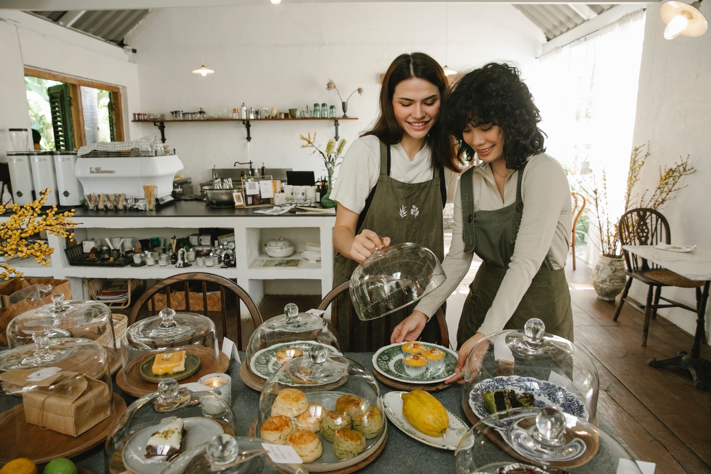 Two owners setting out cakes in their cafe
